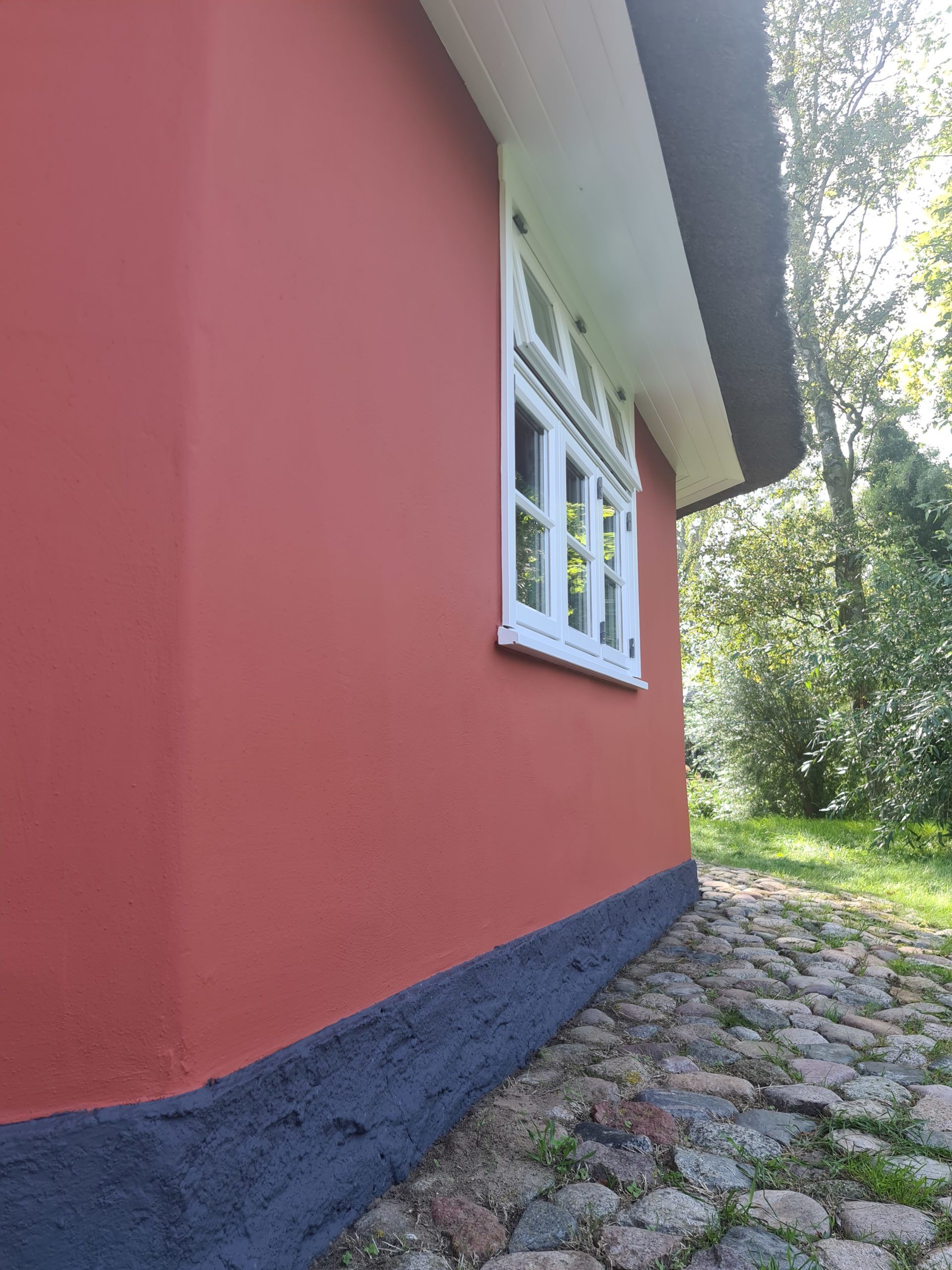 ein rotes Haus mit einem weißen Fenster und einem Steinweg davor .