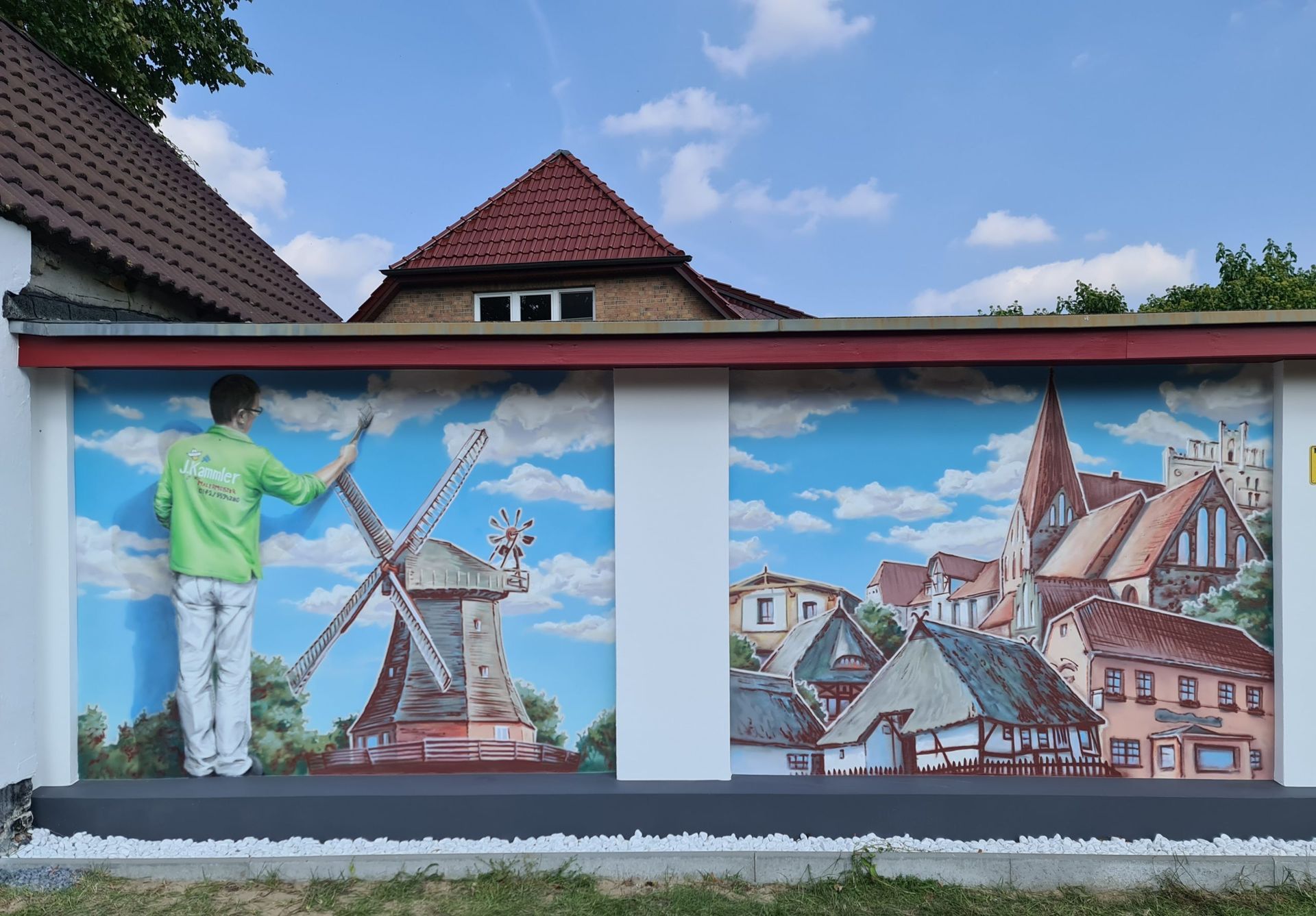 ein Mann malt auf einer Wand eine Windmühle .