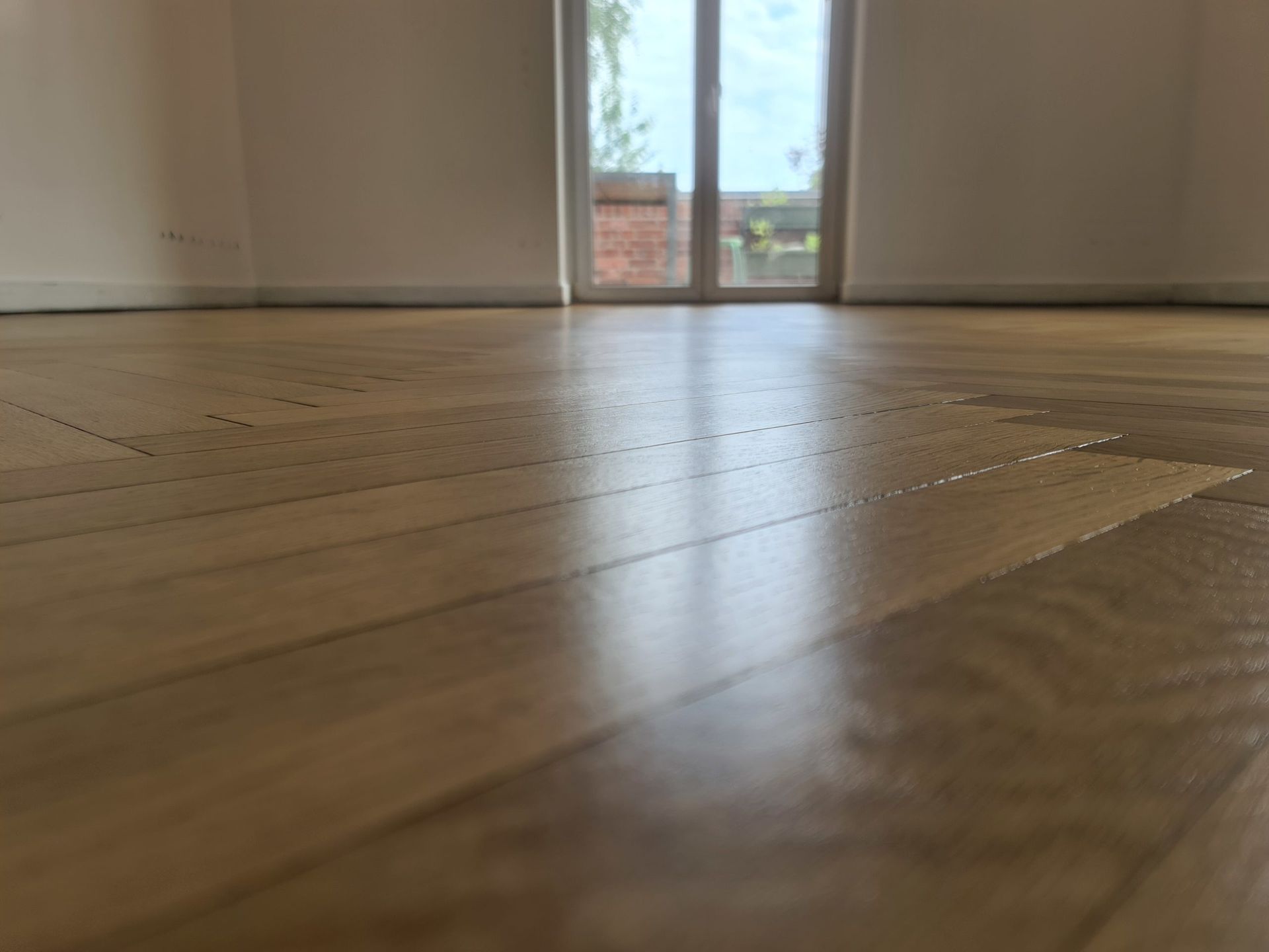 ein leerer Raum mit einem Holzboden und einem Fenster .