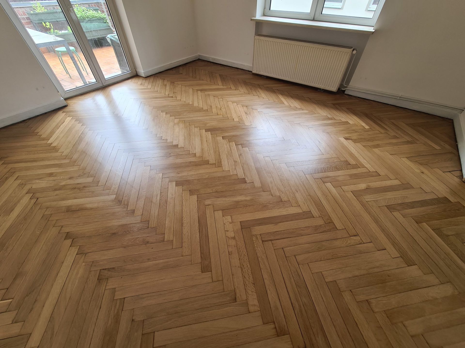 ein Wohnzimmer mit Holzboden und Fenstern .