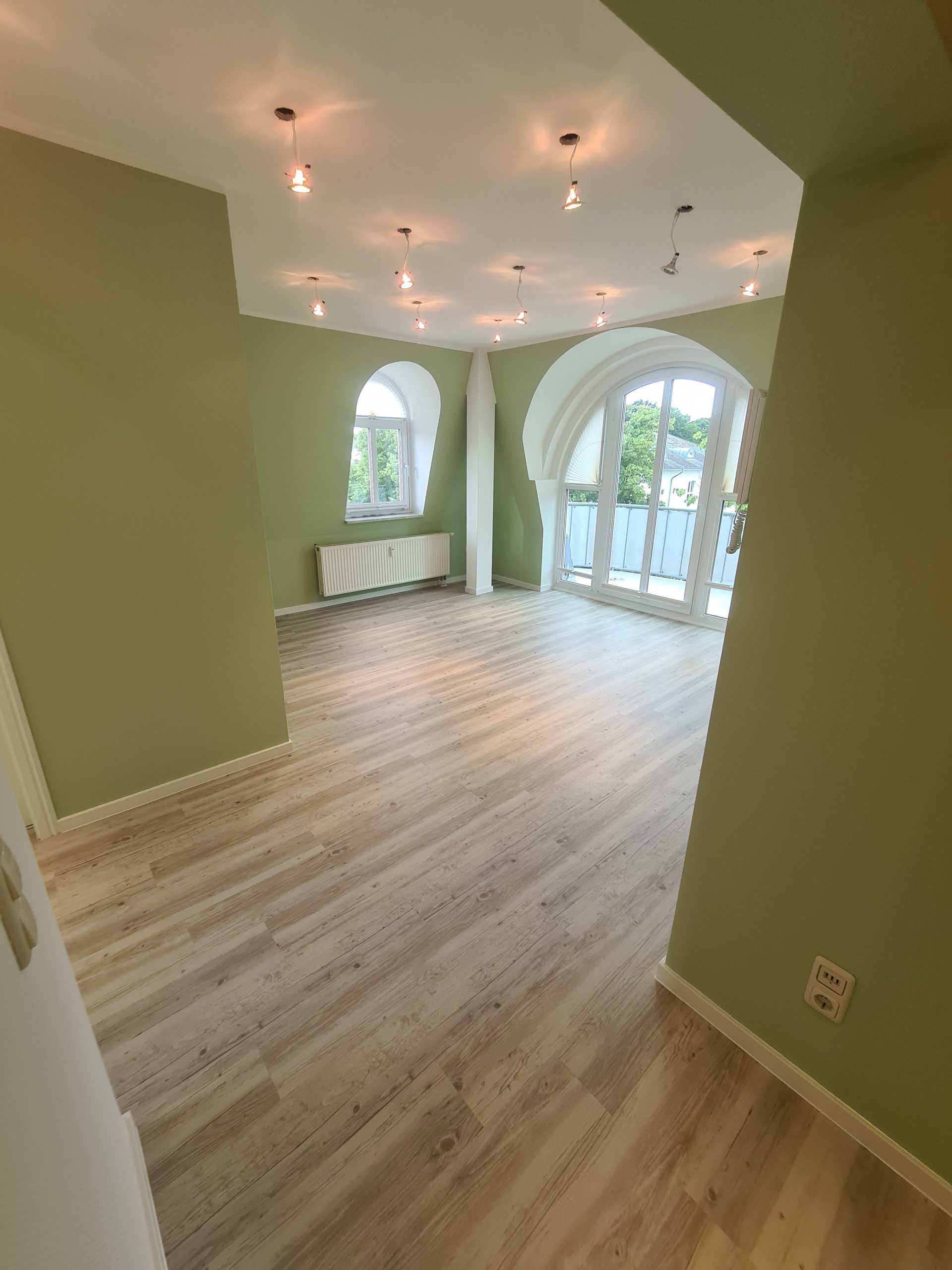 ein leerer Raum mit Holzboden und grünen Wänden . Malerarbeiten in Rostock, Maler