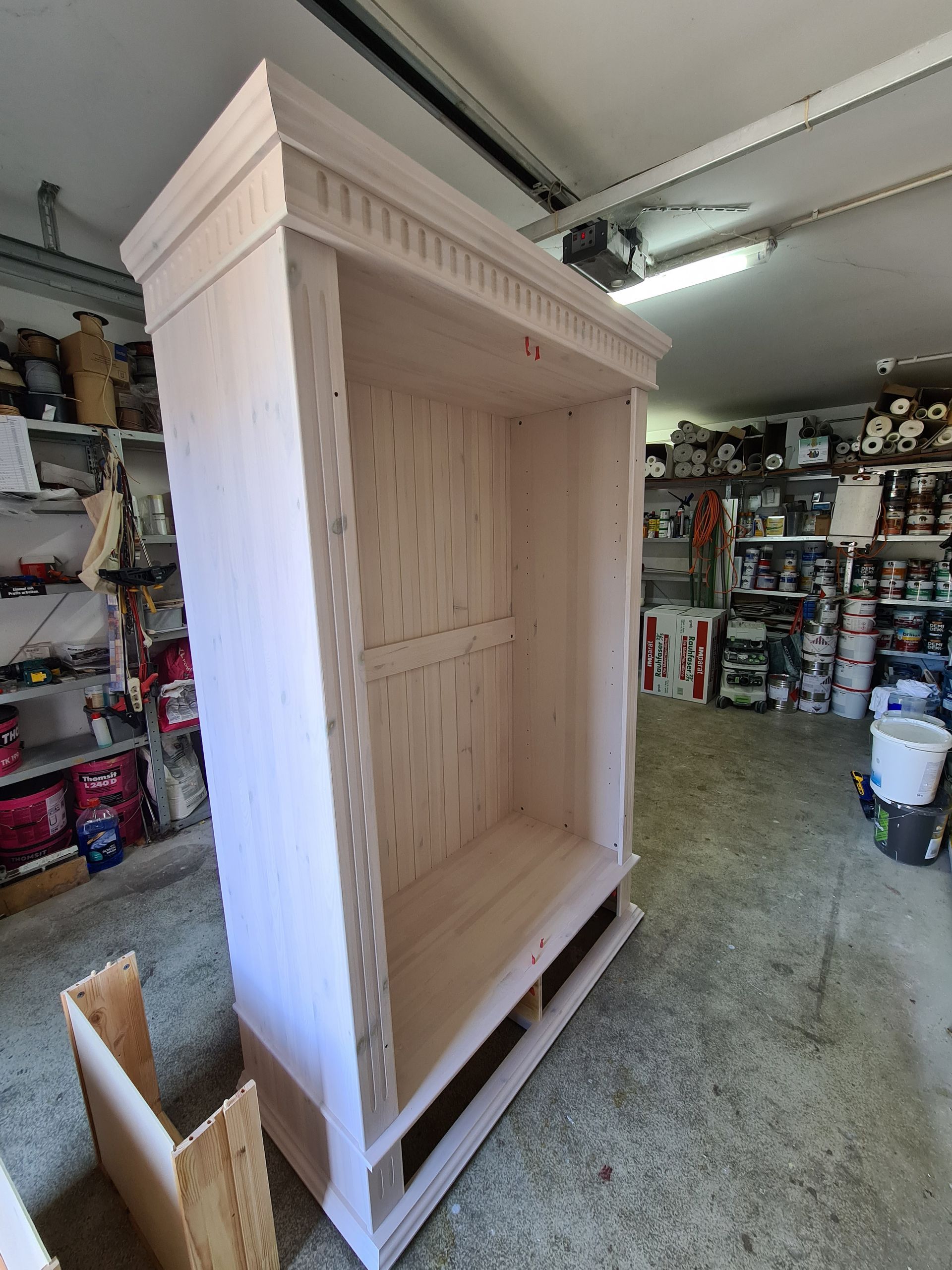 ein großes weißes Holzregal sitzt in einer Garage .