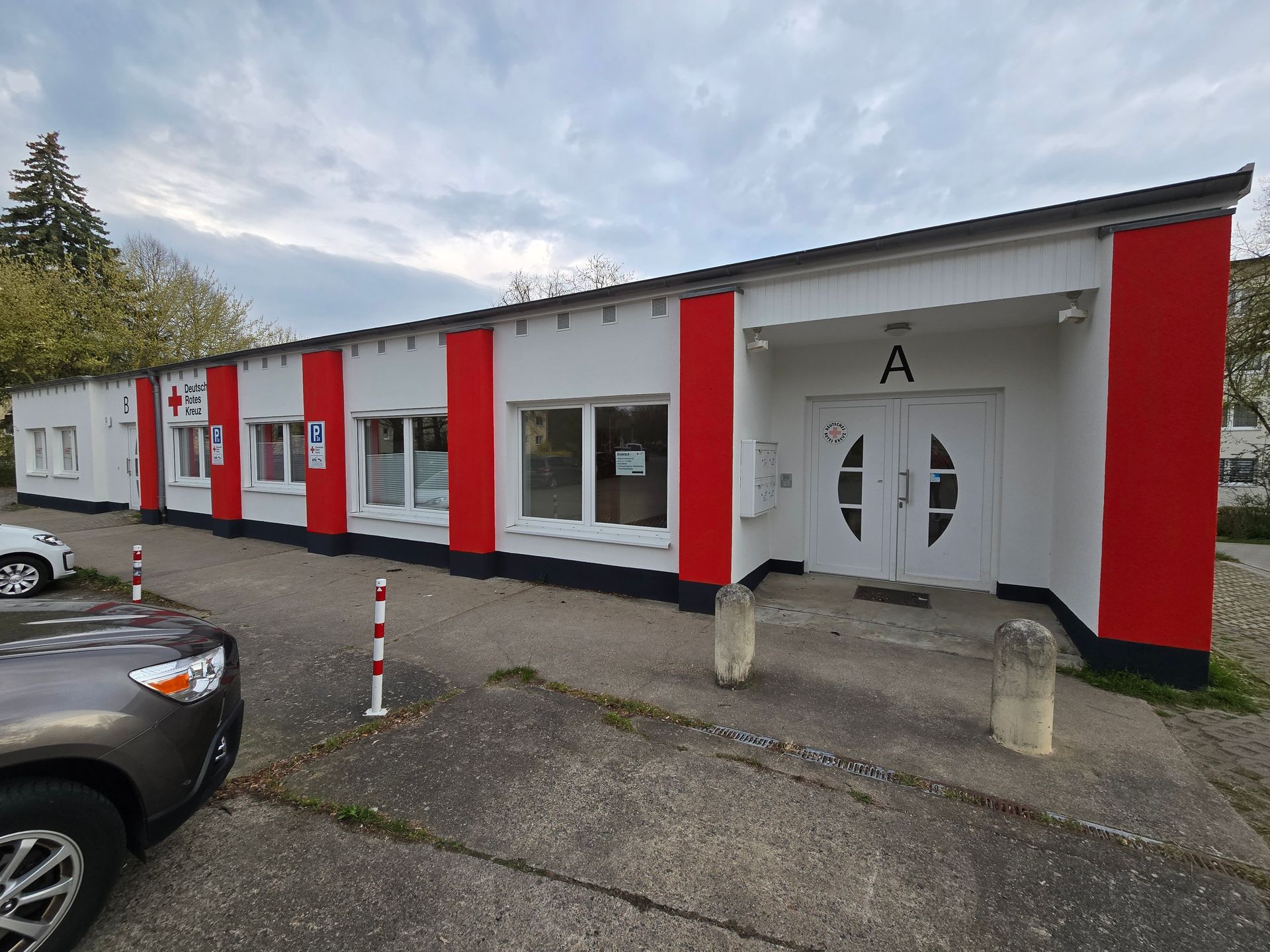 weiße Fassade mit roten streifen und einem Buchstaben A  über der Tür