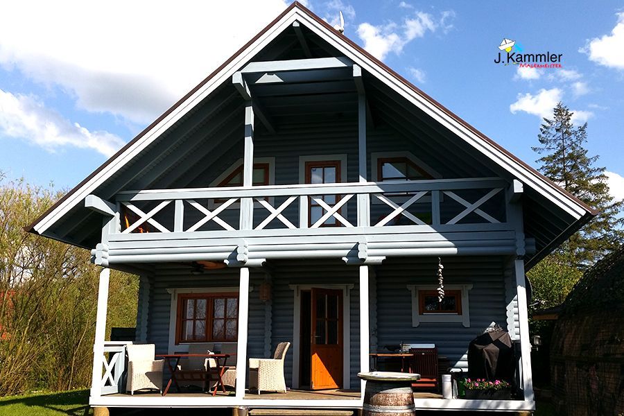ein kleines blaues Holzhaus mit einer Veranda und Möbeln darauf
