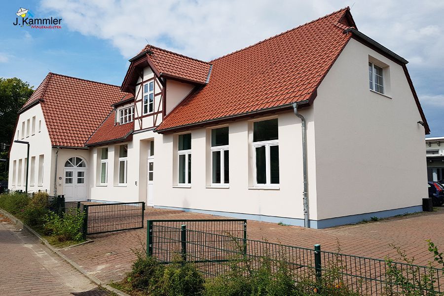 ein großes weißes Haus mit einem roten Dach und vielen Fenstern