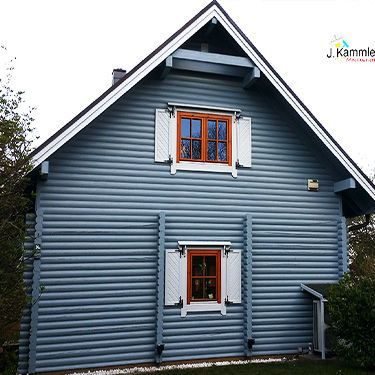 ein blaues Blockhaus mit einem braunen Fenster und weißen Fensterläden