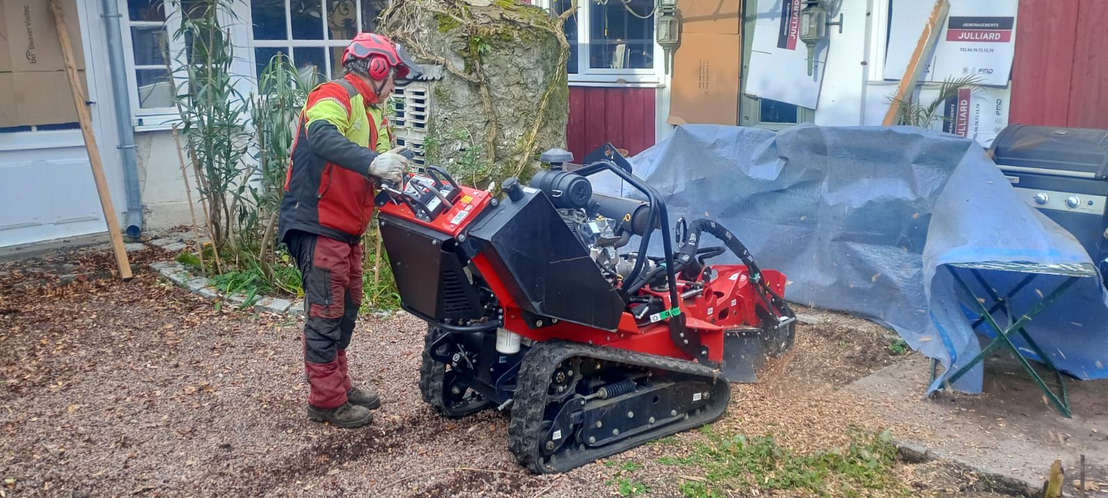 Un ouvrier manœuvre une machine de rognage de souche rouge à côté de bâches