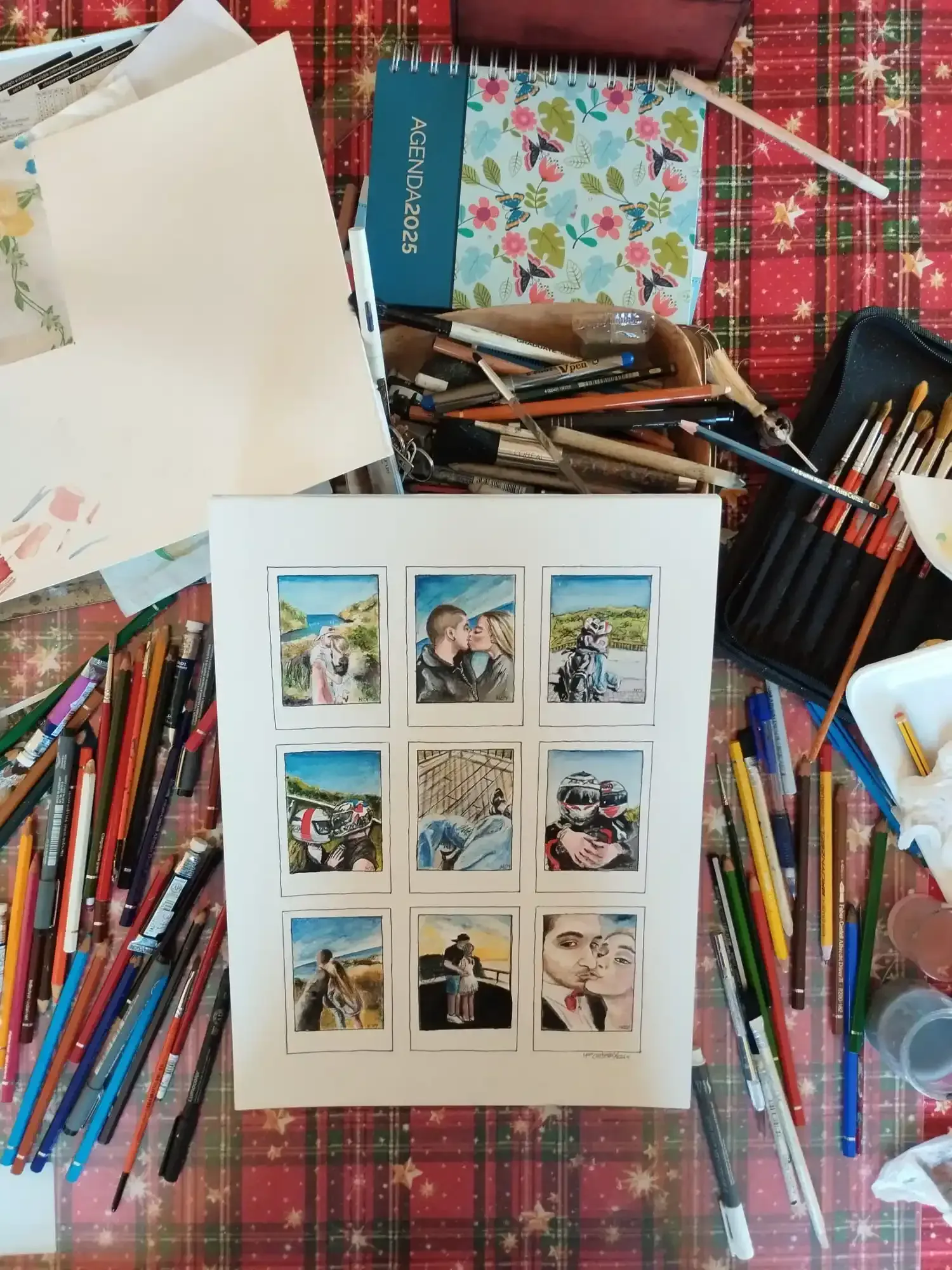 Mesa de manualidades con bolígrafos de colores, papel y un collage de fotos extendido sobre una manta a cuadros.