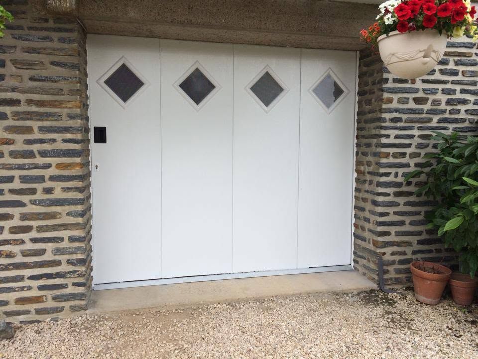 Porte de garage blanche avec trois fenêtres en losange.