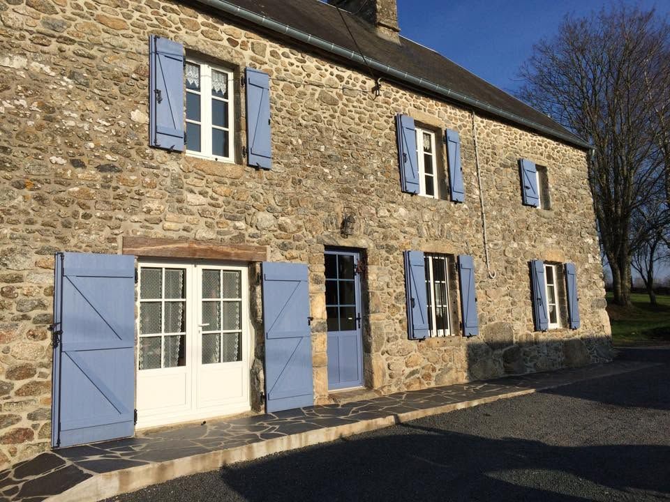 Maisonnette en pierre avec volets bleus et double porte blanche baignée de soleil