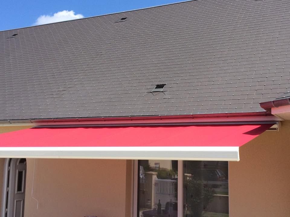 Auvent rouge au-dessus d'une porte sous un toit en bardeaux gris, à l'extérieur d'une maison