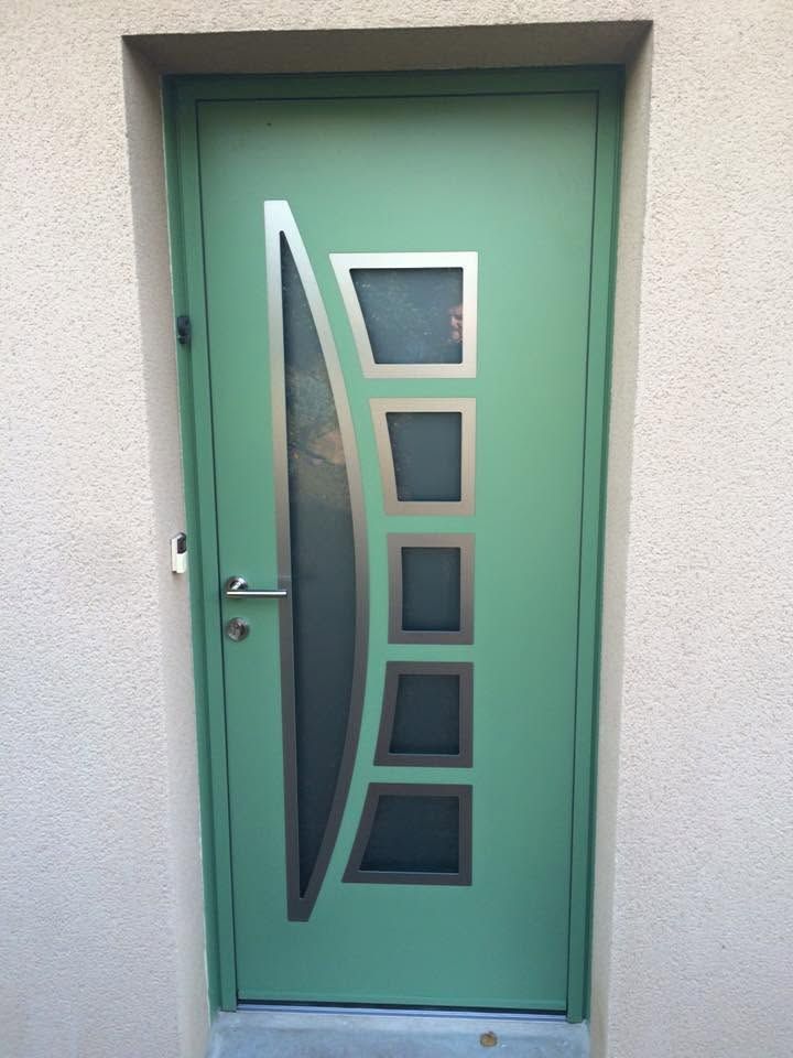 Porte d'entrée vert menthe avec des panneaux de fenêtre verticaux étroits et une poignée argentée.