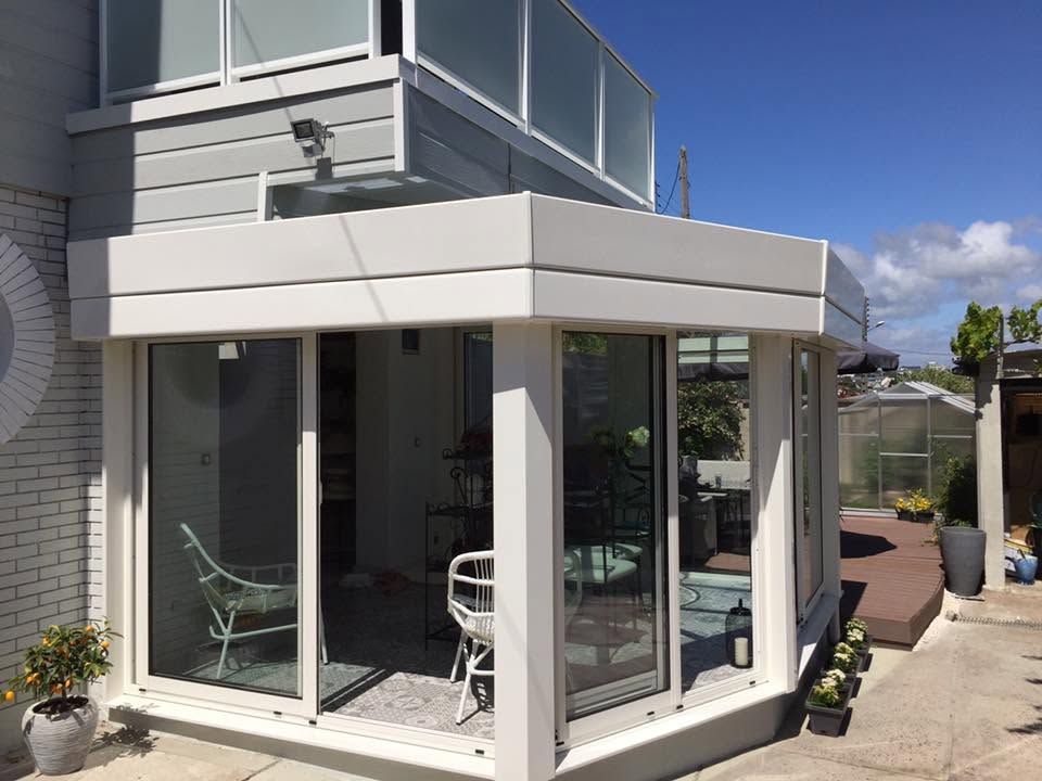 Maison d'angle moderne blanche avec de grandes baies vitrées et un petit patio sous un ciel bleu