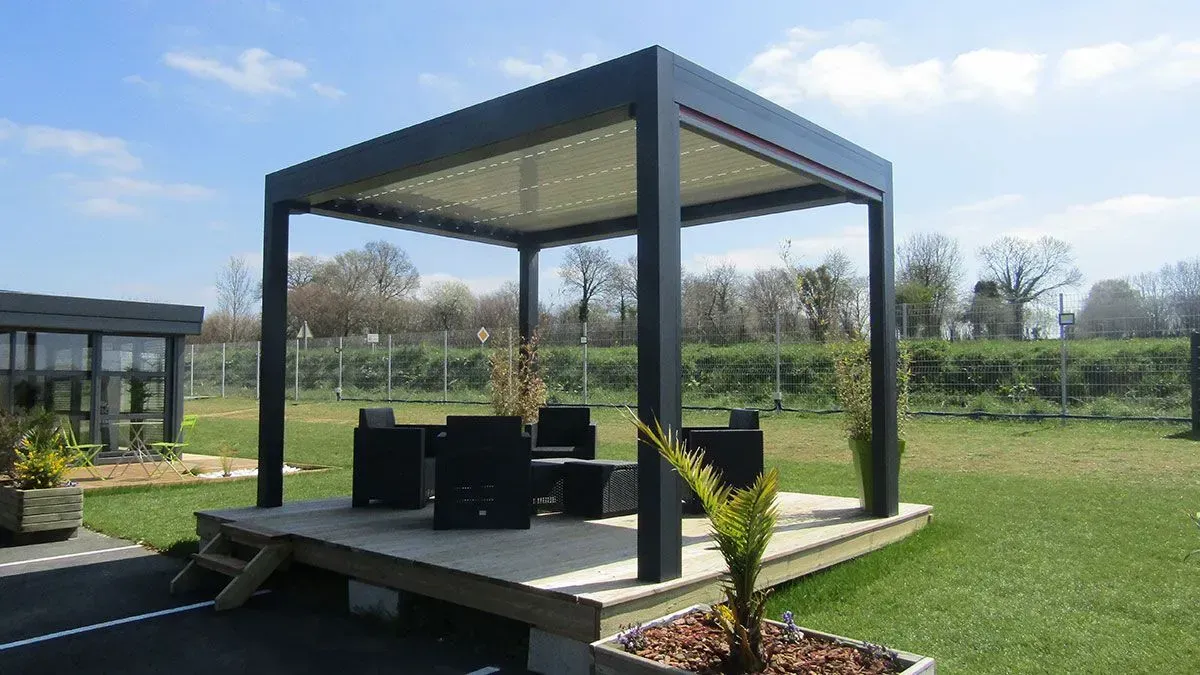 Pergola noire avec sièges sur une terrasse en bois dans un parc verdoyant par une journée ensoleillée