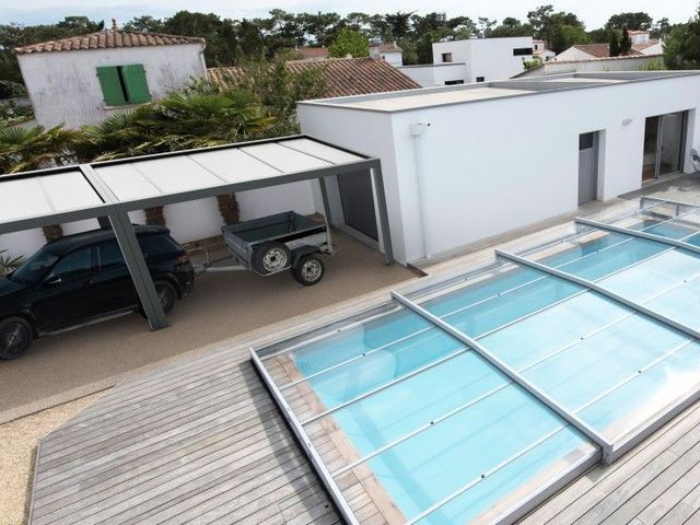Vue depuis le toit sur des bâtiments blancs, des véhicules stationnés et une piscine couverte de verre