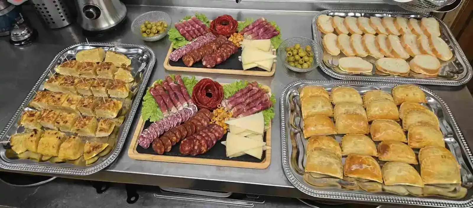 Platos de comida: fiambres, quesos, aperitivos, aceitunas y pan.