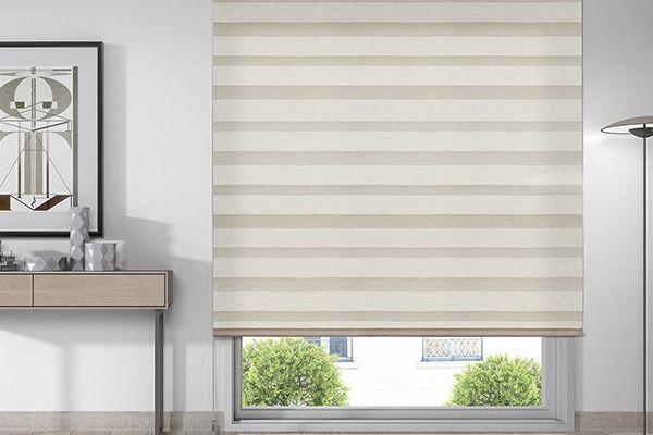 Estor de rayas beige que cubre una ventana, con vistas a la vegetación de abajo.