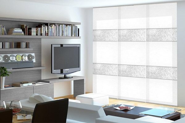 Salón moderno con persianas blancas, mueble de televisión gris y sofá.