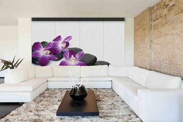 Sofá seccional blanco en una sala de estar moderna con un mural de orquídeas moradas y piedras negras.