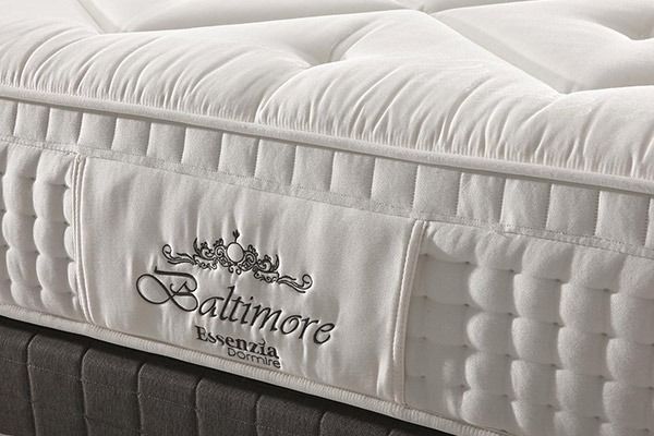 Primer plano de un colchón blanco Baltimore con logotipo bordado y parte superior capitoné.
