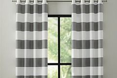 Cortinas a rayas grises y blancas enmarcan una ventana.
