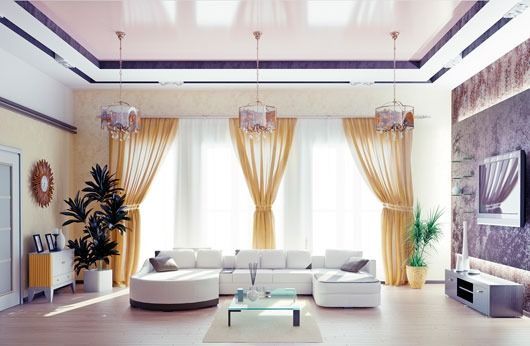 Sala de estar con sofá blanco, cortinas doradas, tres lámparas colgantes, plantas y un televisor.