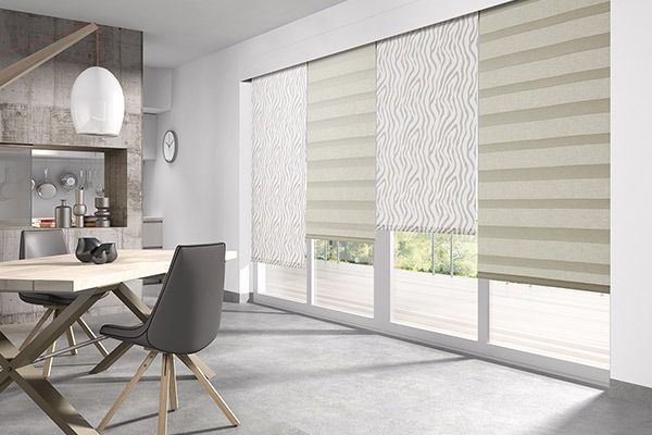 Comedor con mesa y sillas grises, y persianas de ventanas de capas de color claro.