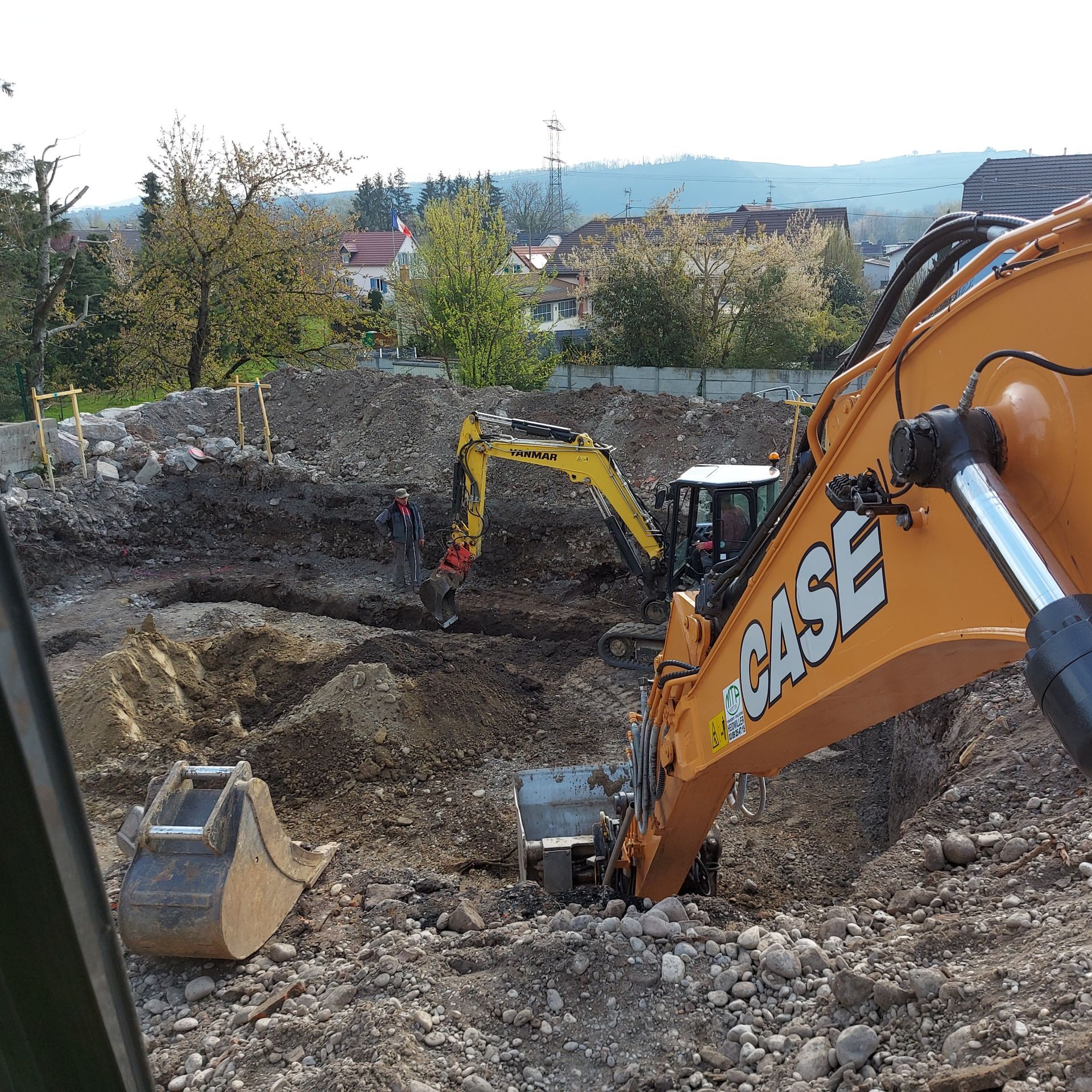 Une excavatrice décaisse un terrain.