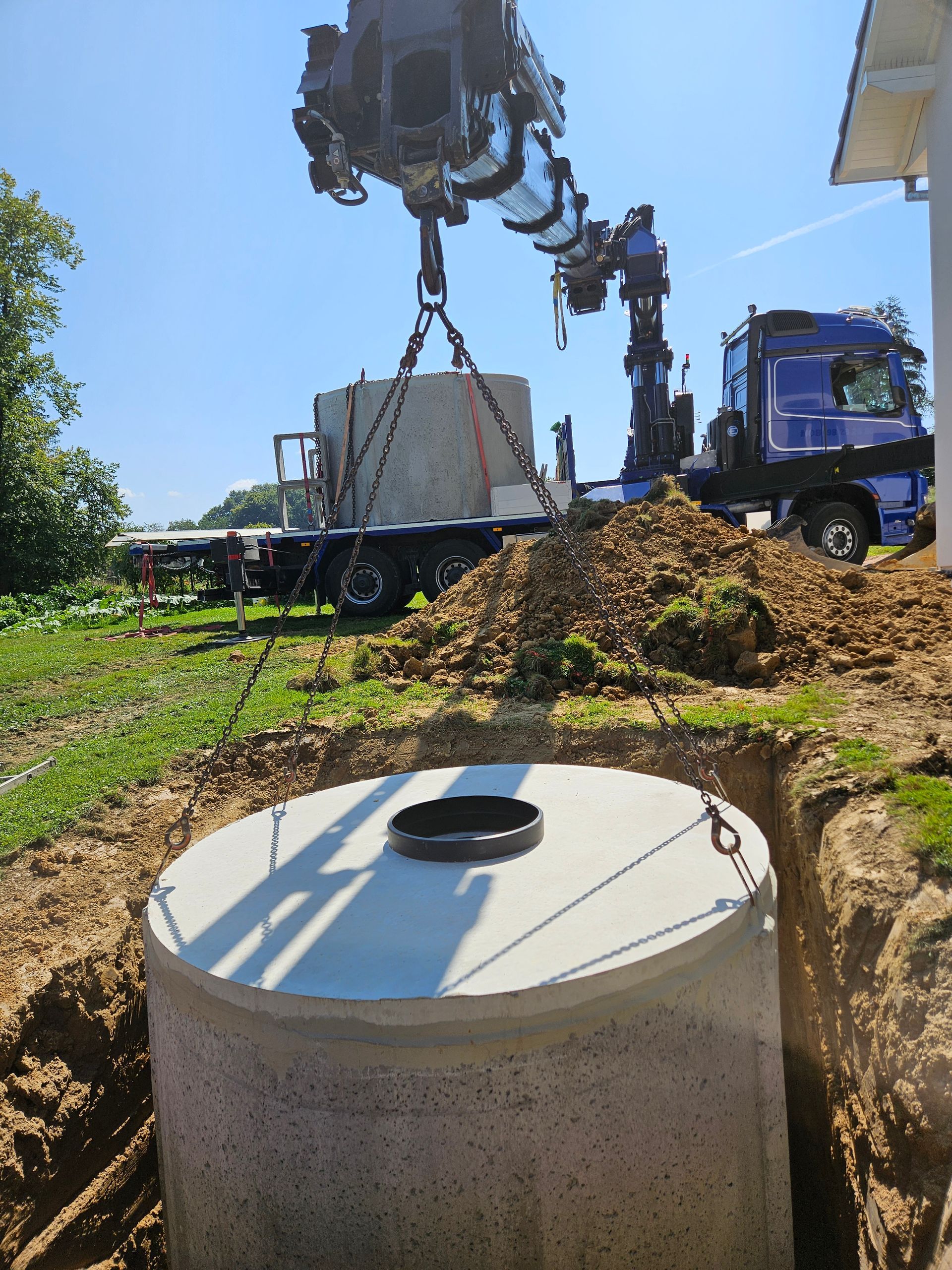 Chantier de construction avec une grue soulevant une cuve à eau en béton.