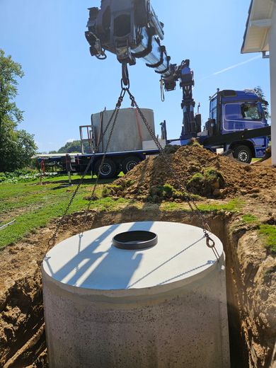 Chantier de construction avec une grue soulevant une cuve à eau en béton.