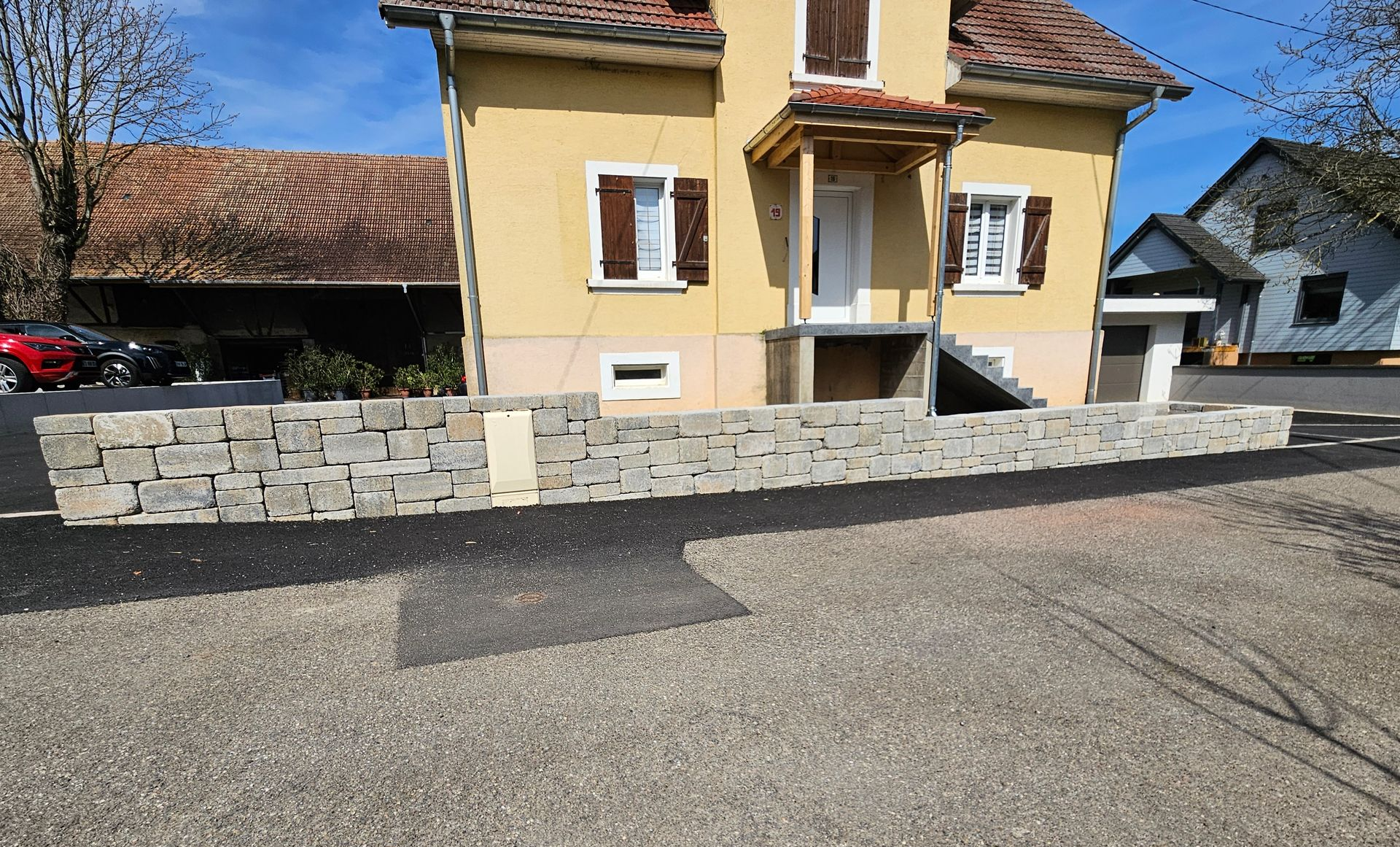 Un muret en pierre devant une maison.