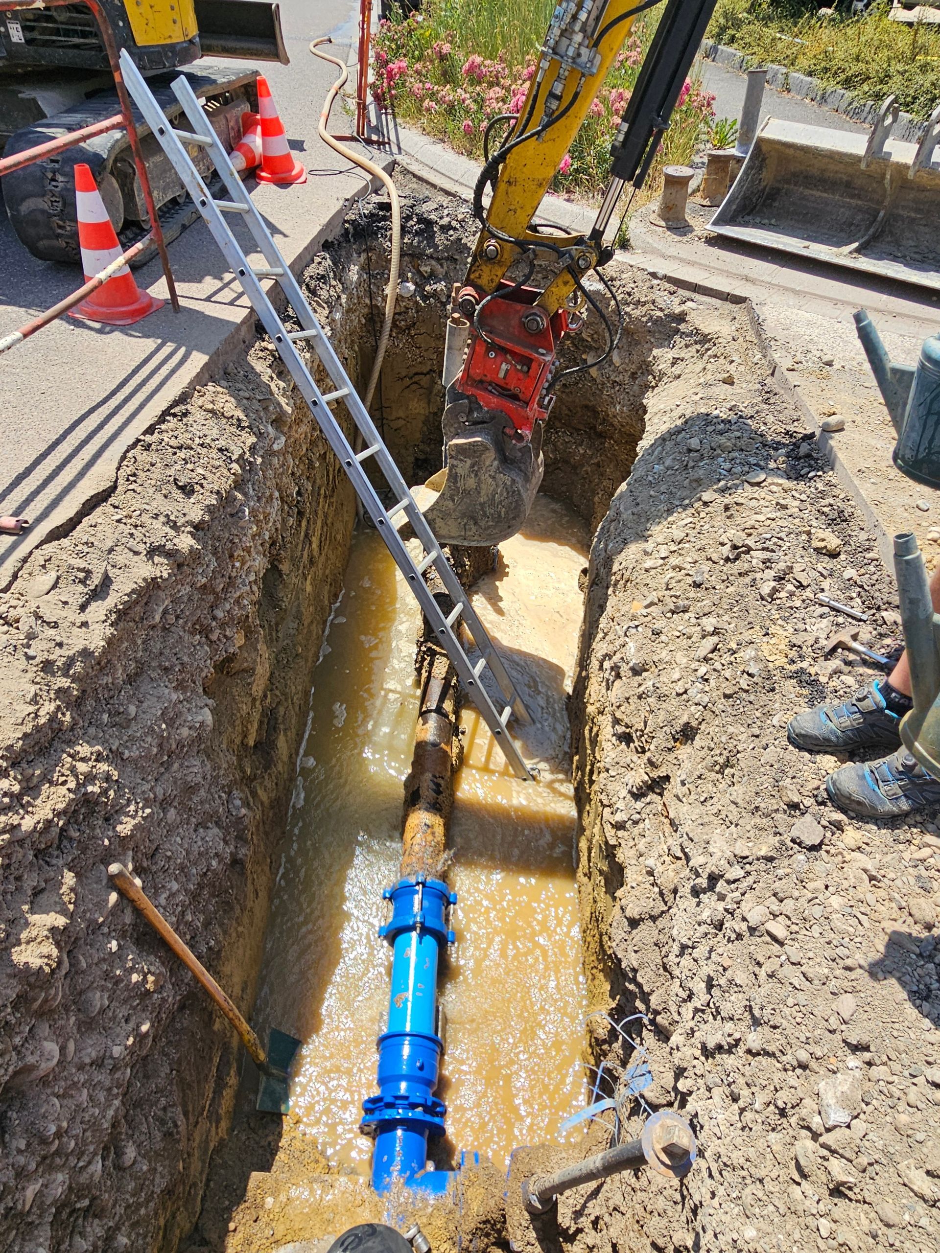 Une tranchée remplie d'eau avec une canalisation d'eau potable.