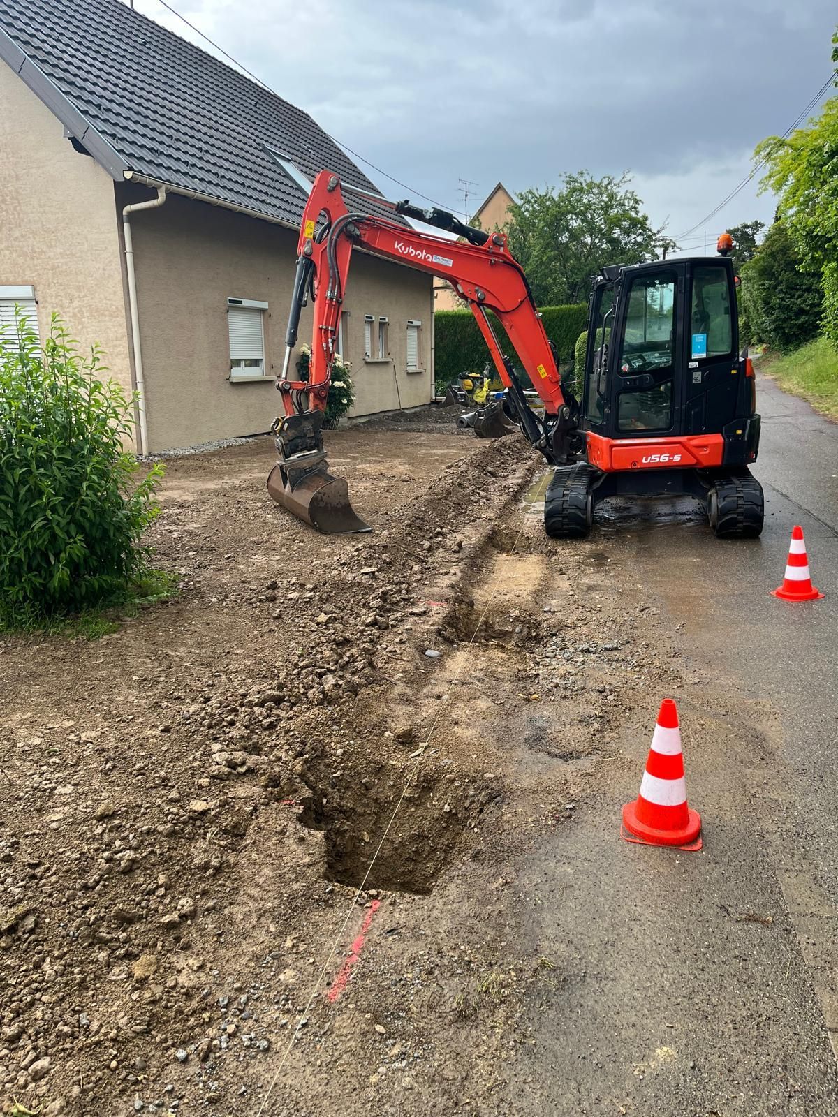 Un engin de chantier au bord d'une route avec une tranchée.
