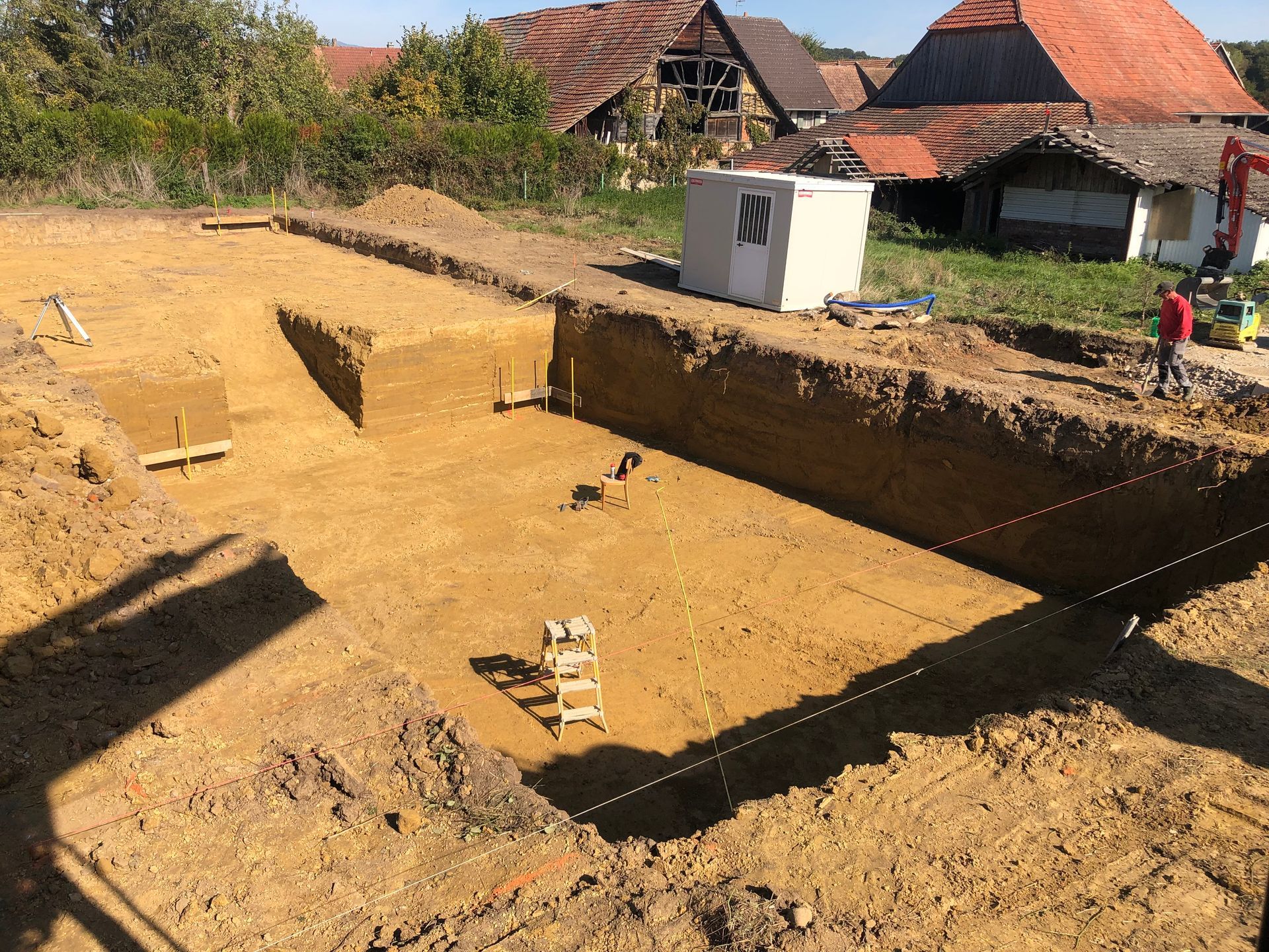 Des travaux de terrassement avec des tranchées et un engin de chantier.