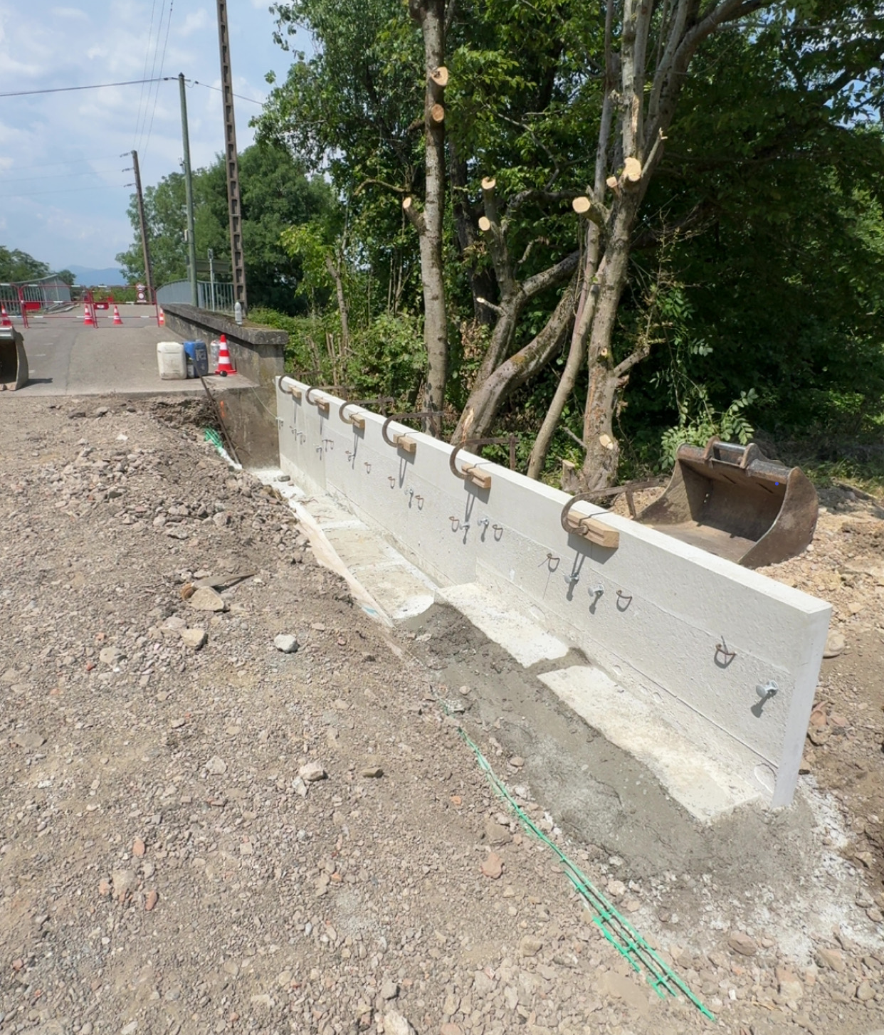 Dalles de fondation en construction sur un terrain entouré d'arbres.