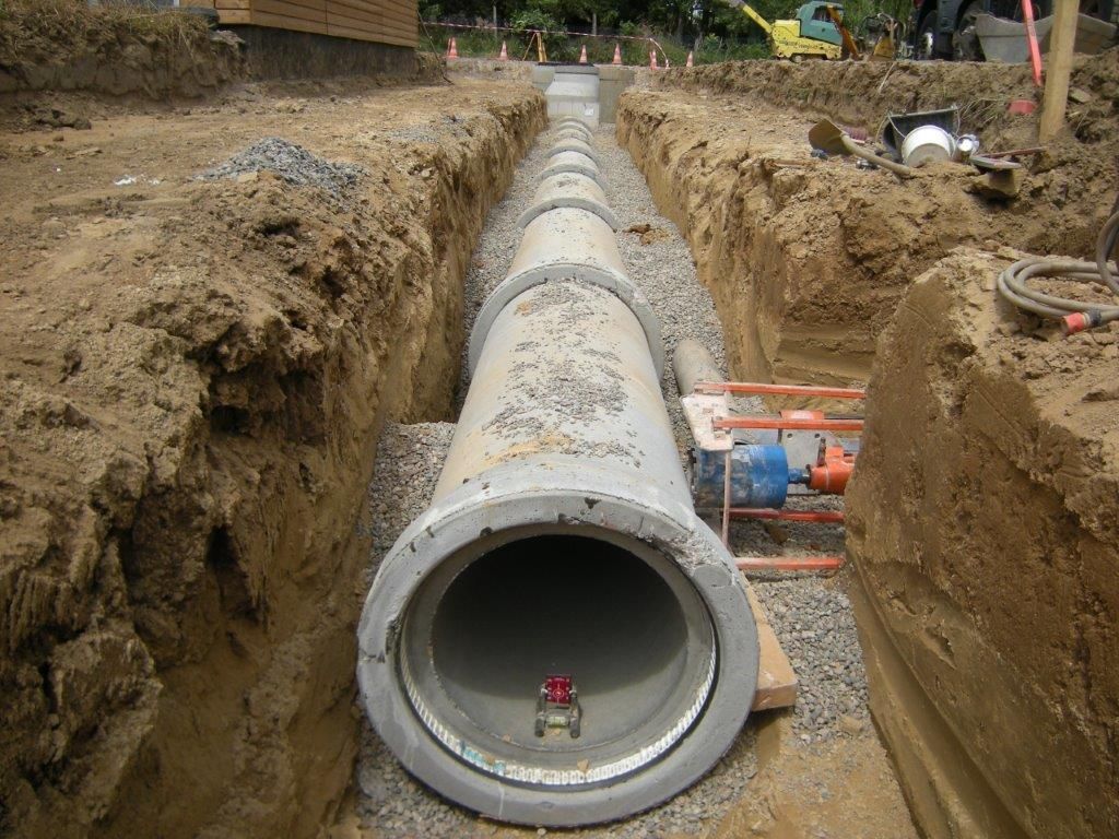Une canalisation en béton posé dans une tranchée sur un chantier.