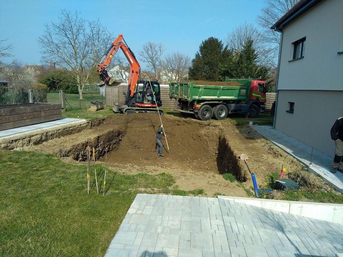 Une excavatrice décaisse un terrain.