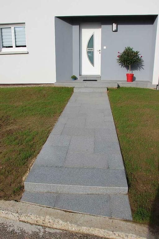 Allée d'entrée en dalles grises menant à une maison.
