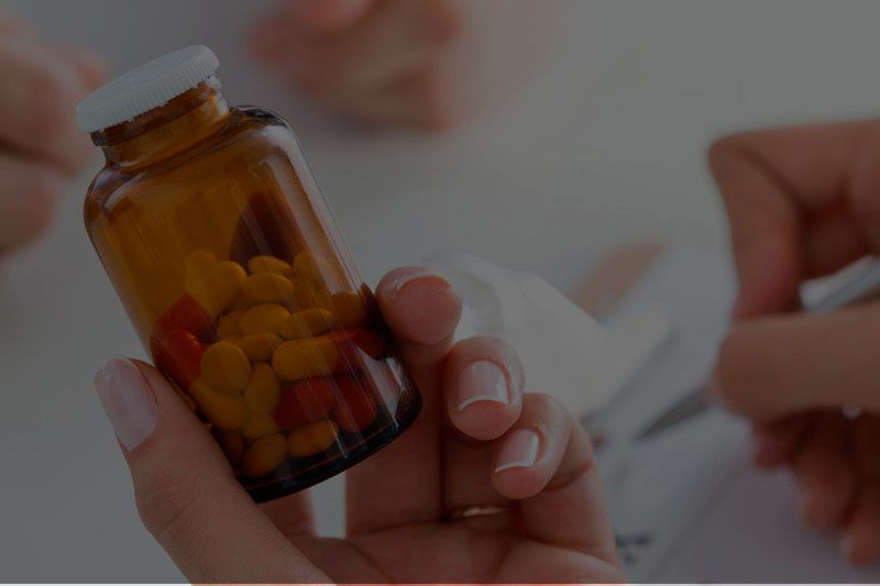 Una persona sostiene un frasco de pastillas en su mano.