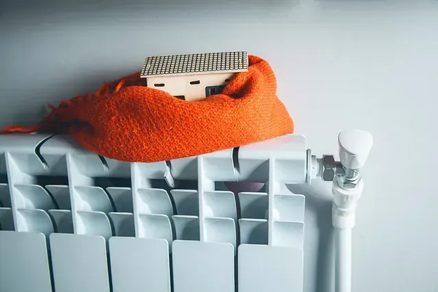 Una pequeña casa está envuelta en una bufanda naranja sobre un radiador.
