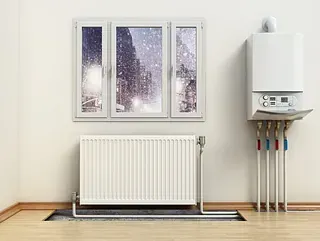 Una habitación con un radiador y una caldera al lado de una ventana.