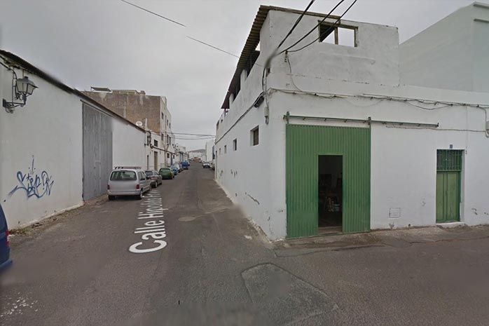 Una calle con un edificio blanco y una puerta verde.
