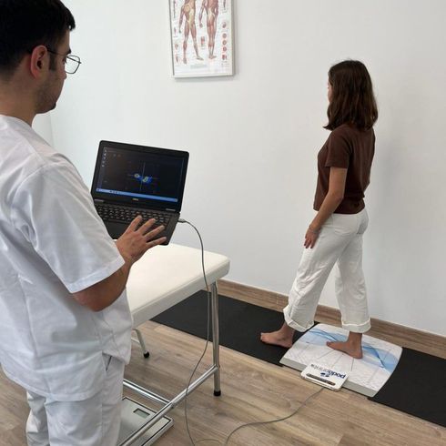 Un médico analiza datos en un ordenador portátil mientras un paciente permanece descalzo