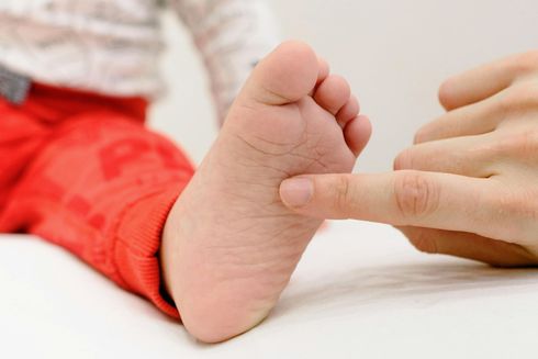 El dedo de una persona toca suavemente la planta del pie de un niño pequeño