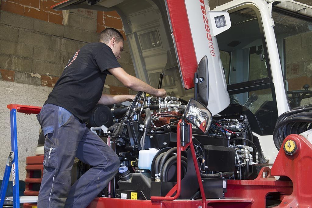 Employé d'AMAT TP en train d'effectuer la réparation d'un moteur d'engin de travaux publics