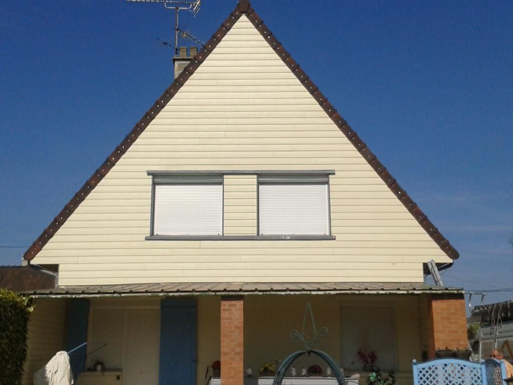 Une maison avec des bardages et deux fenêtres.