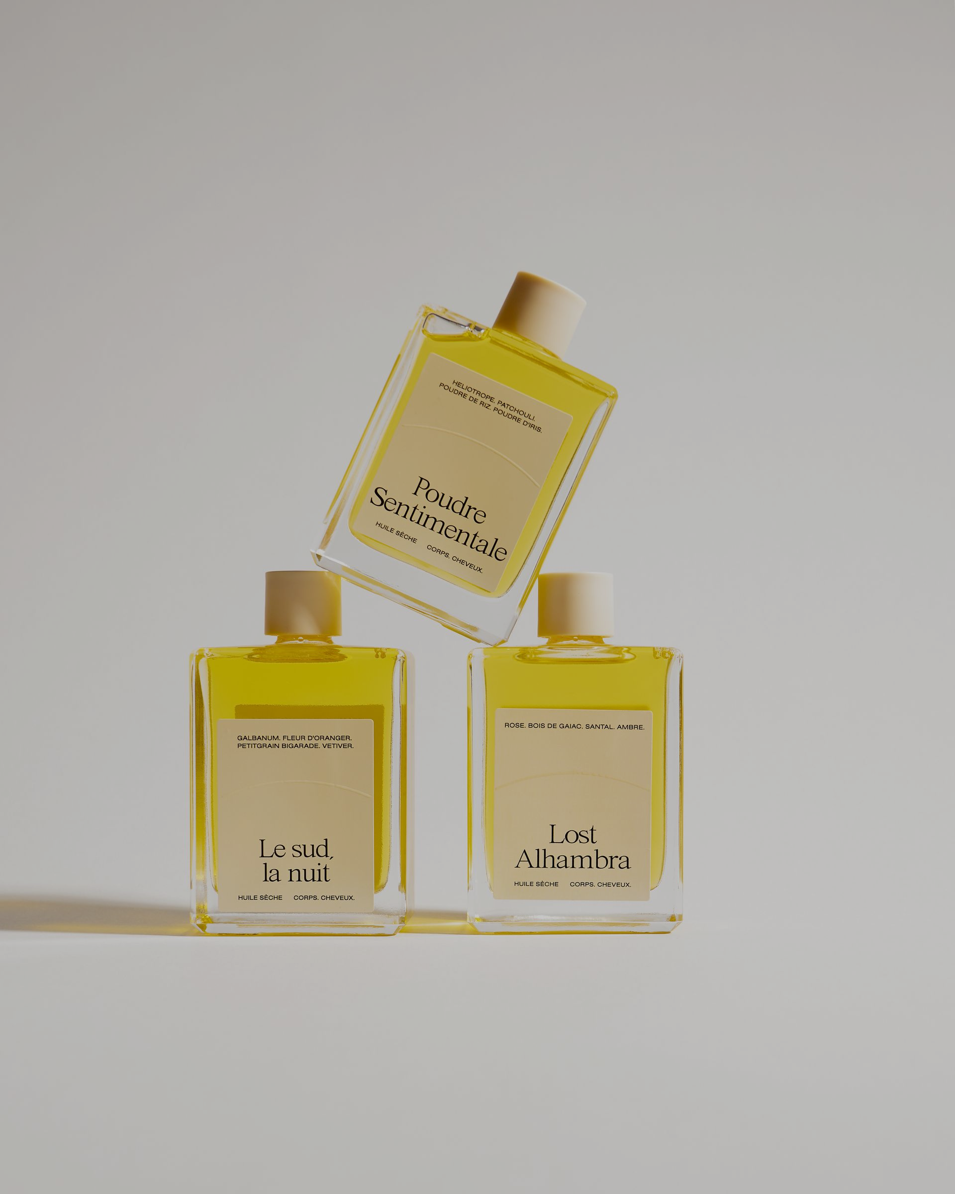 Portant avec vêtements aux tons neutres. Chaussures, sacs à main et chapeau exposés à proximité. Lumière traversant les stores.