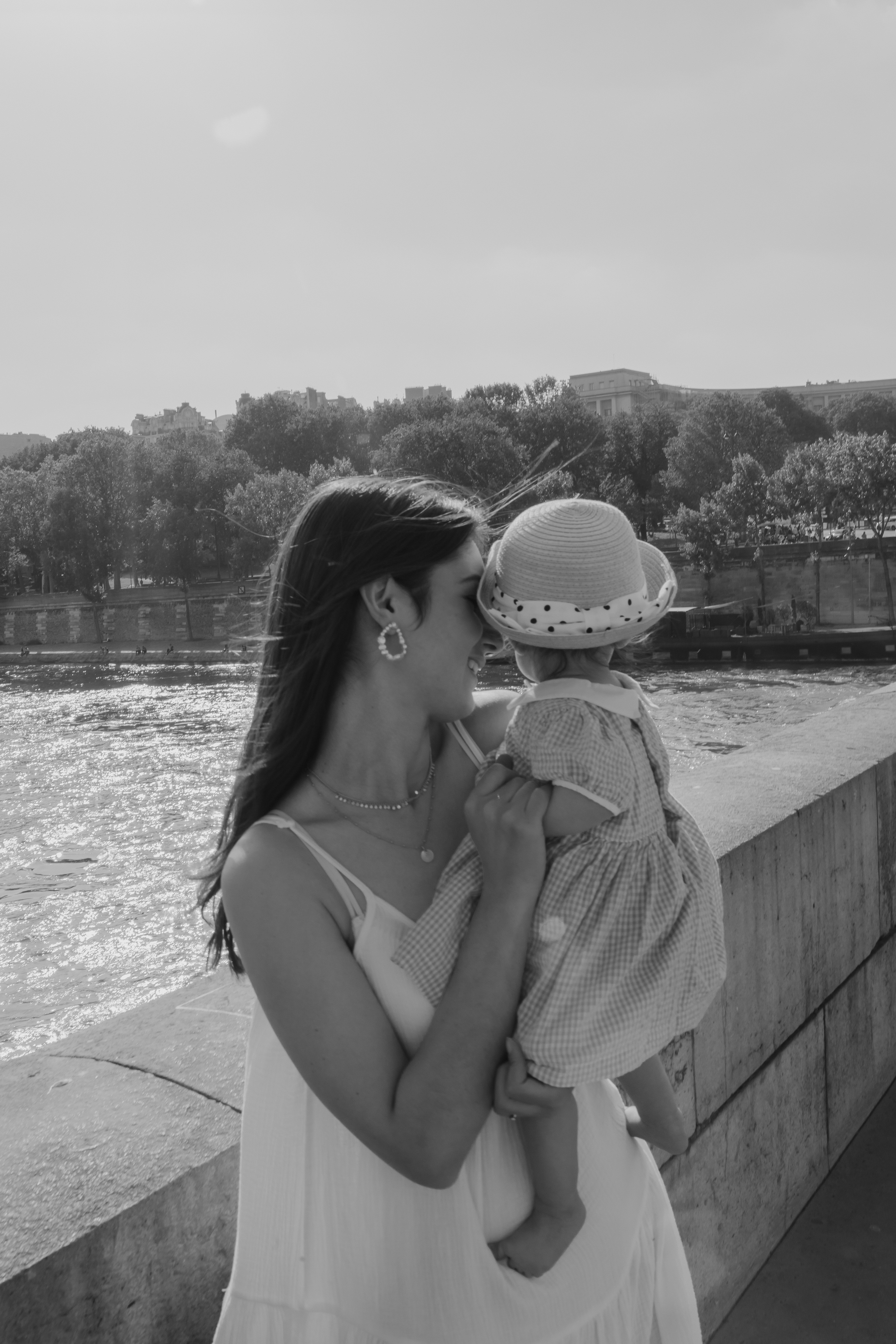 Bouteille noire sur une plage de sable, partiellement immergée dans de l'eau mousseuse.