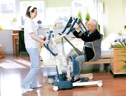 Una enfermera levanta a un anciano en un hospital.
