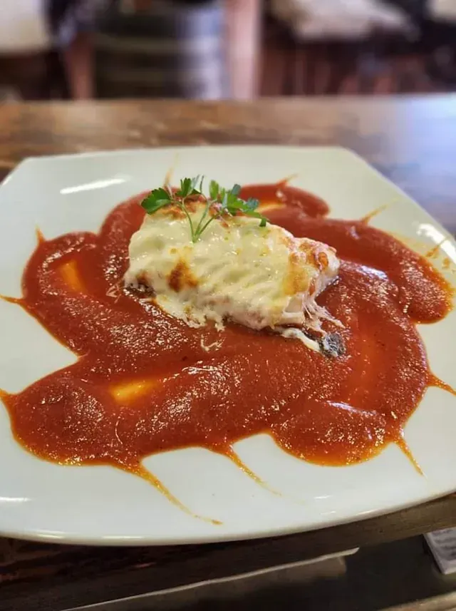 Un plato blanco cubierto con salsa de tomate y queso.